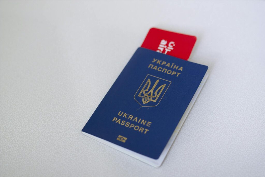 Blue Ukraine passport with airplane ticket on white surface. Travel concept.
