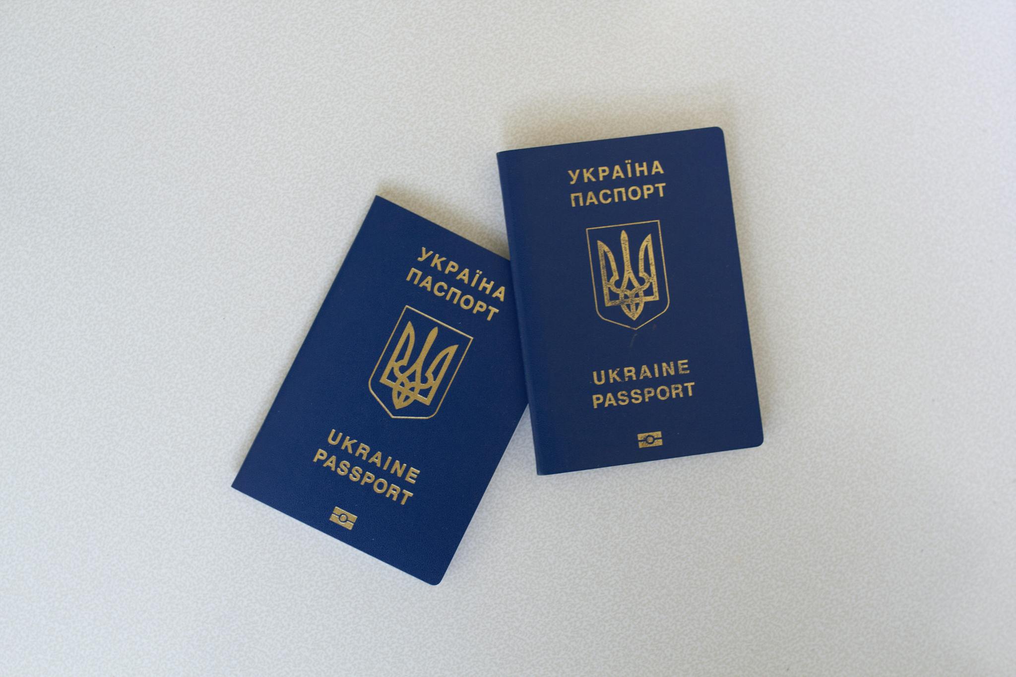Two Ukrainian passports placed on a white surface in a flat lay style.